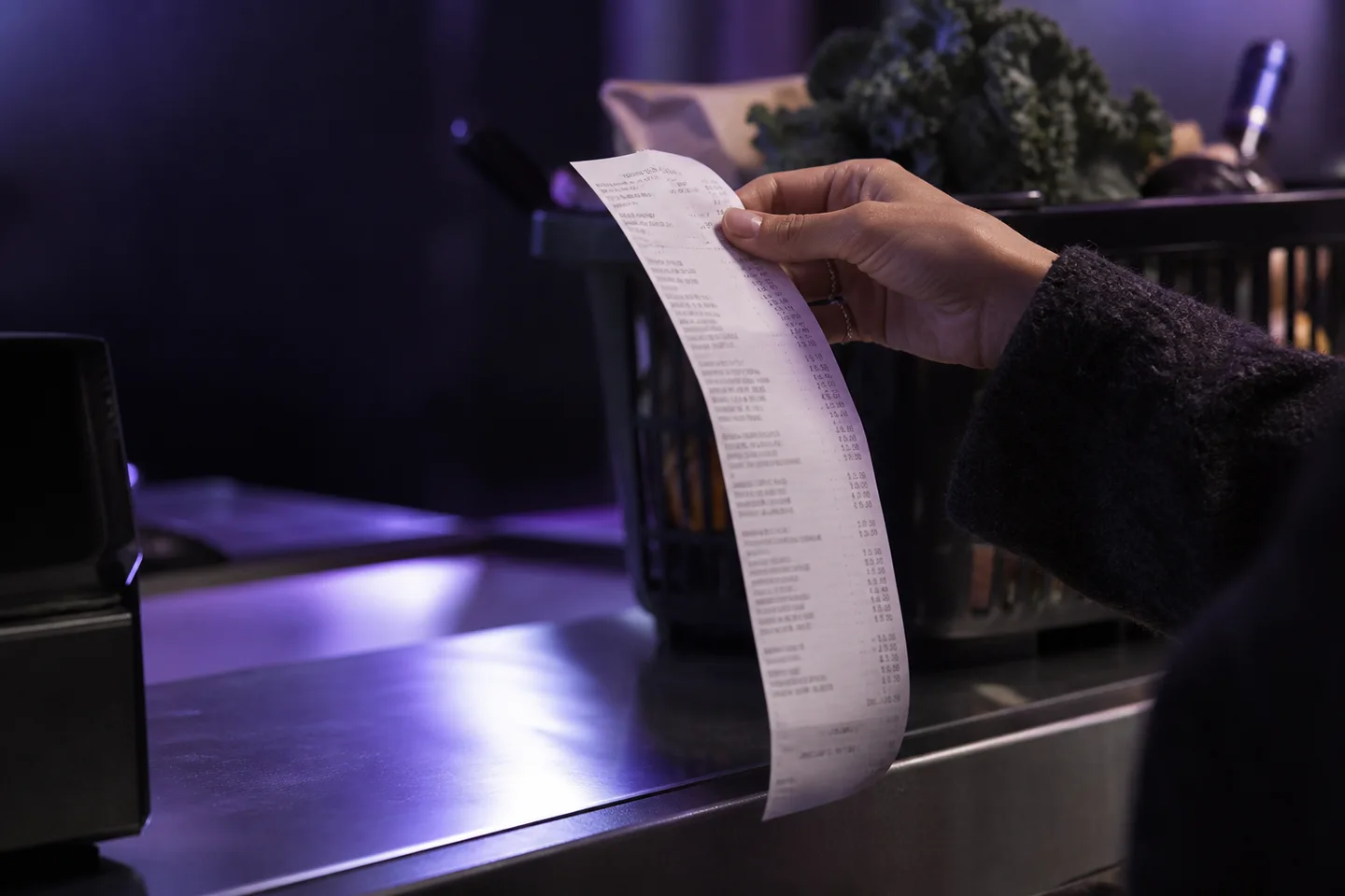 A shopper holding a receipt at a grocery checkout.